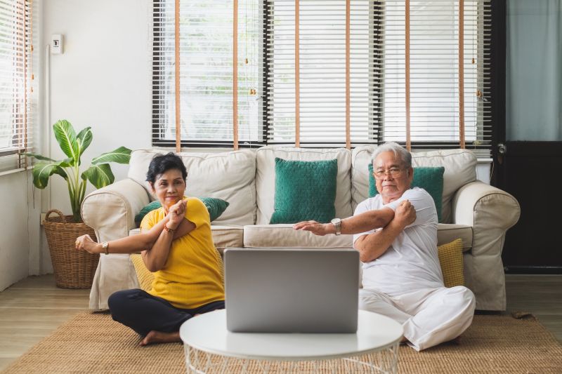 Two seniors following online exercise at home