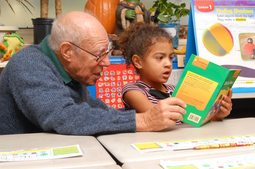 older volunteer reads with child