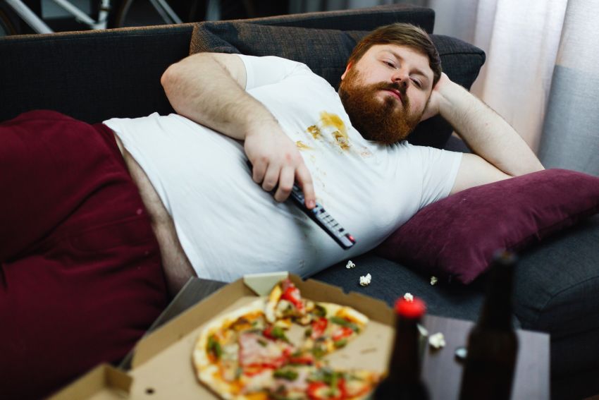 sedentary fat man lies sofa watches tv 